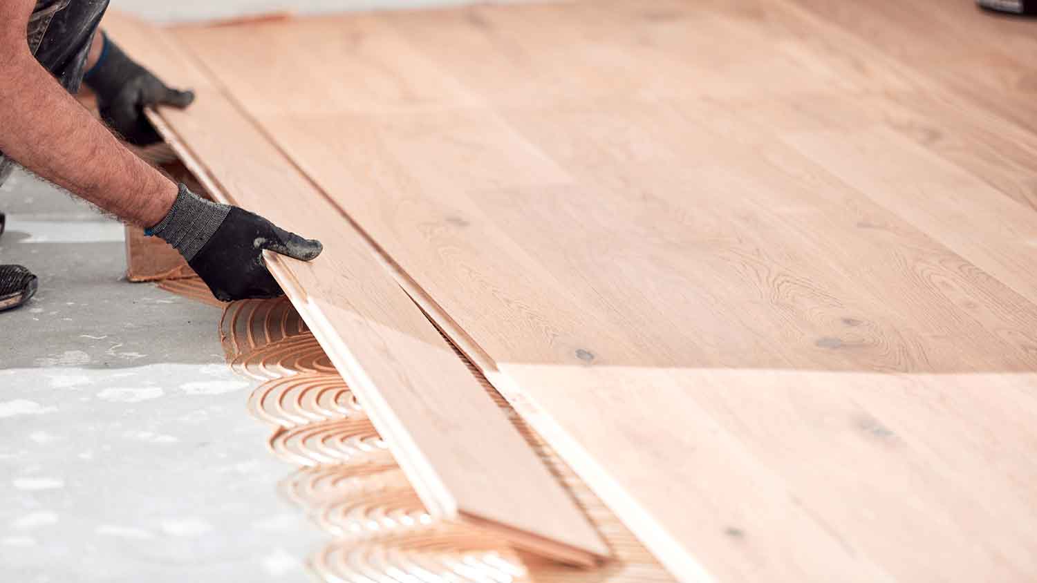 Handyperson installing engineered wood flooring in the room