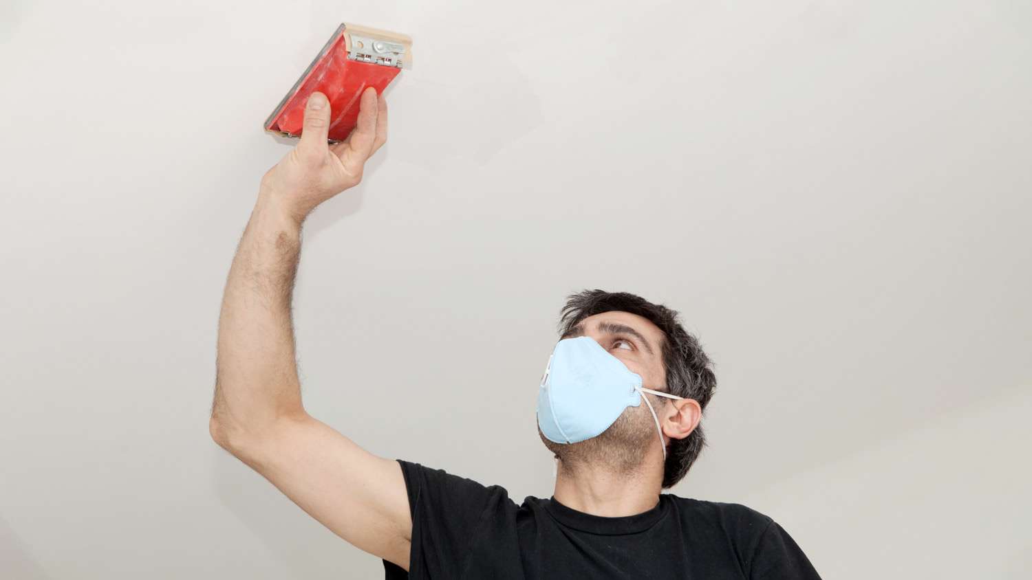 A man sanding the ceiling