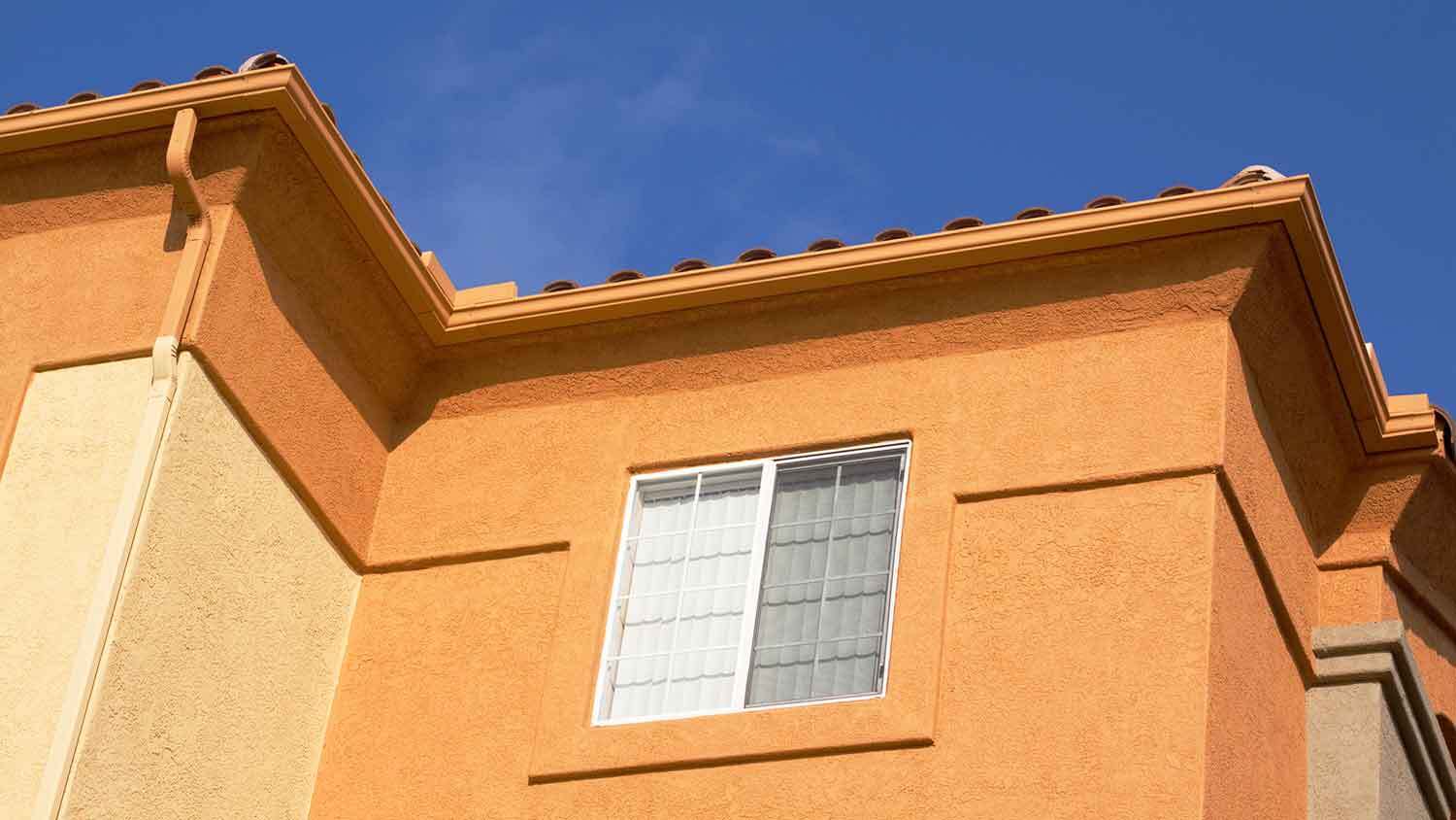 Bright orange house exterior with lace and skip stucco finish
