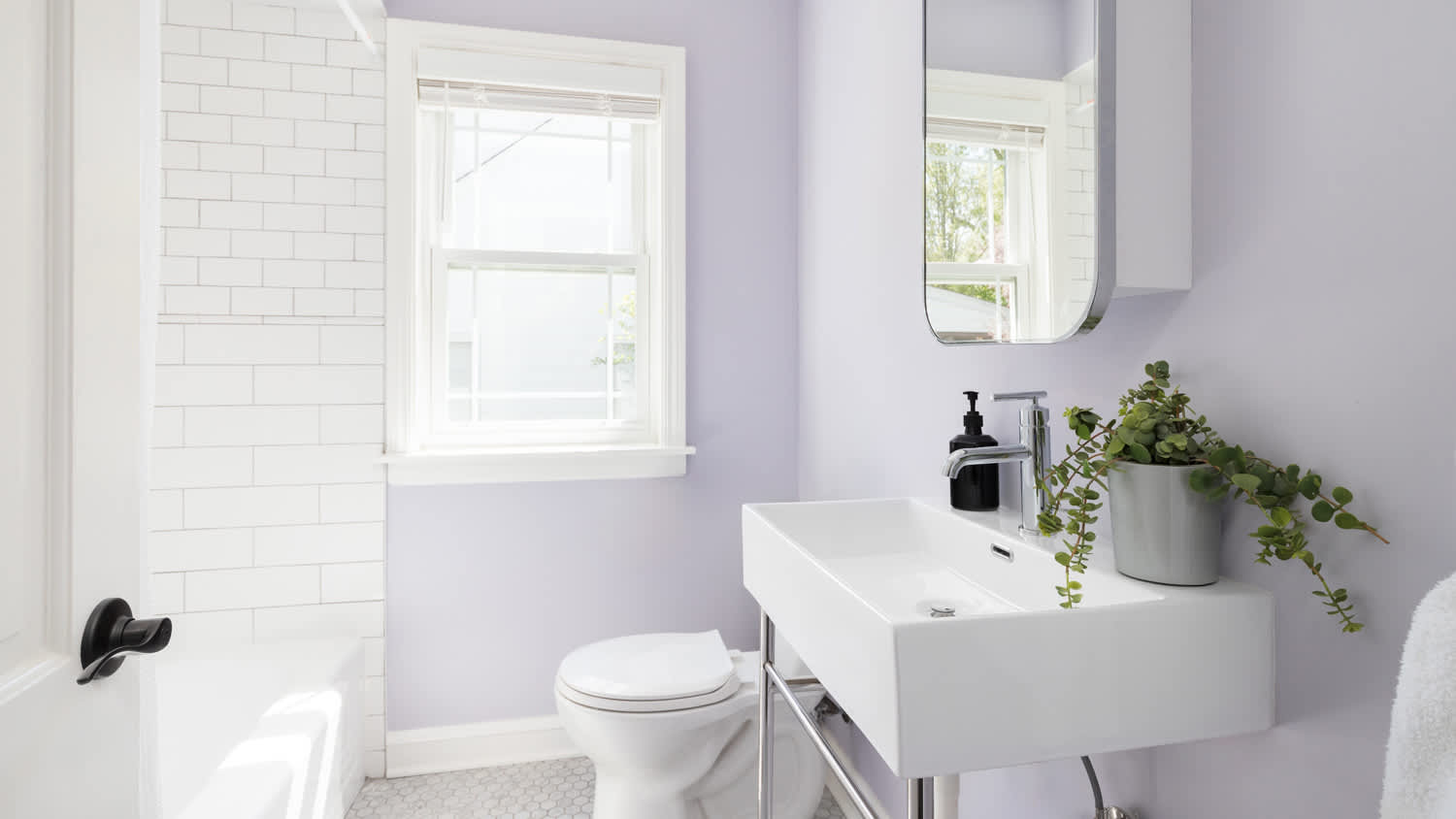 A bathroom with purple walls and white subway tile shower