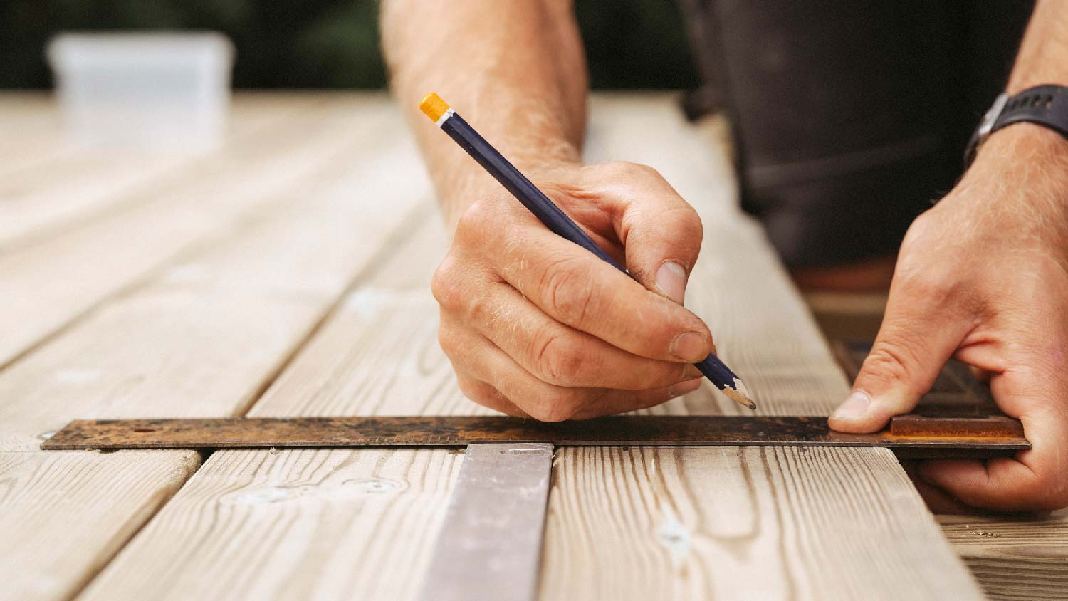A man measuring a wooden deck’s boards