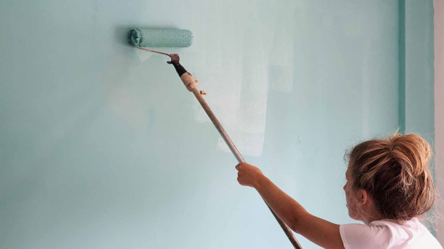 Woman roller painting a wall