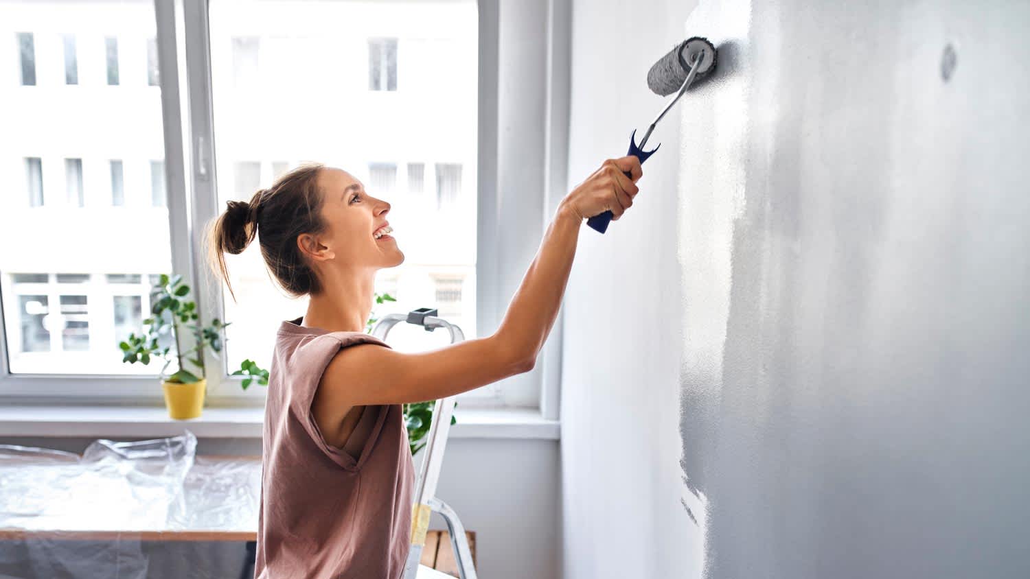 woman painting wall gray