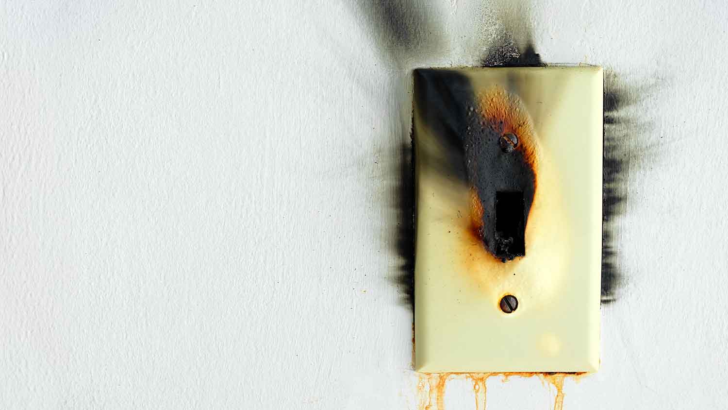 Burnt electrical switch mounted on a white wall