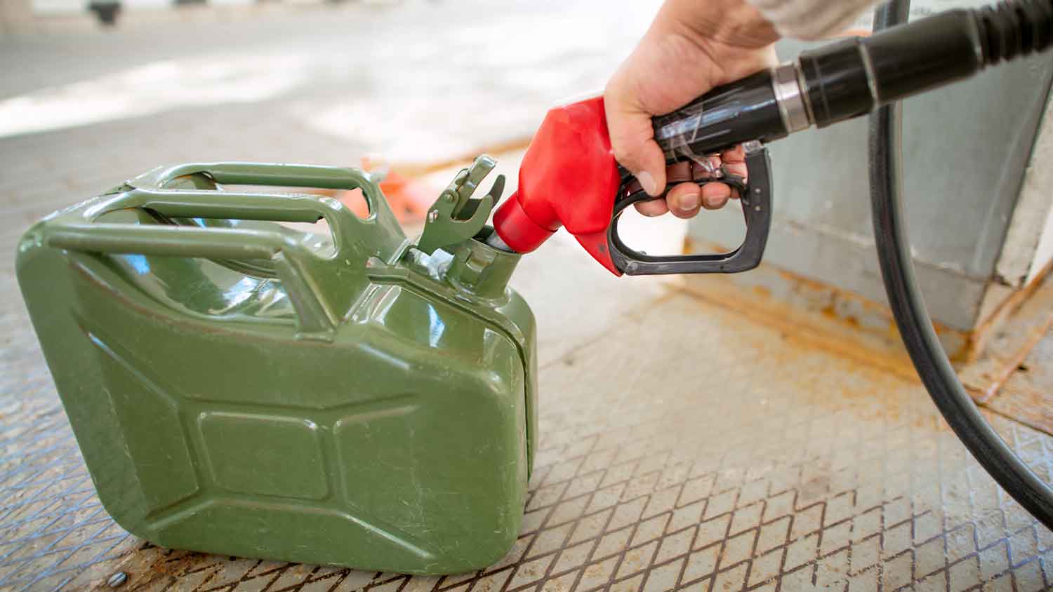 Person filling up gas can at a gas station
