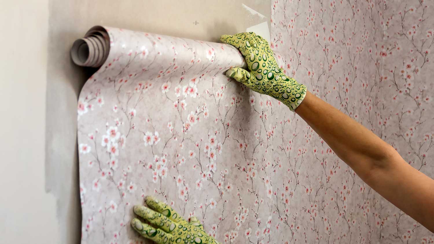 A woman installing a wallpaper on a wall