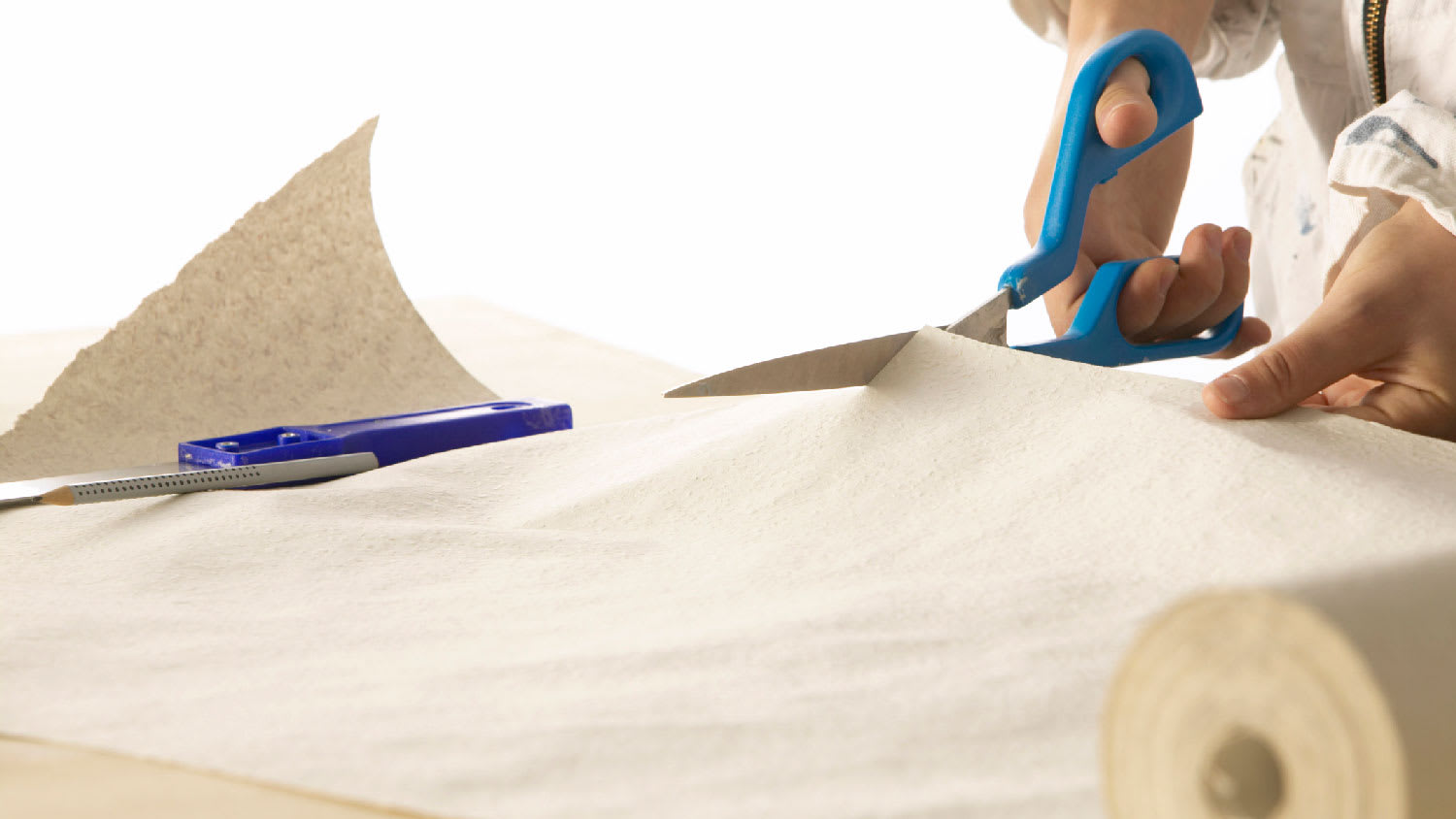 A person cutting a wallpaper with scissors