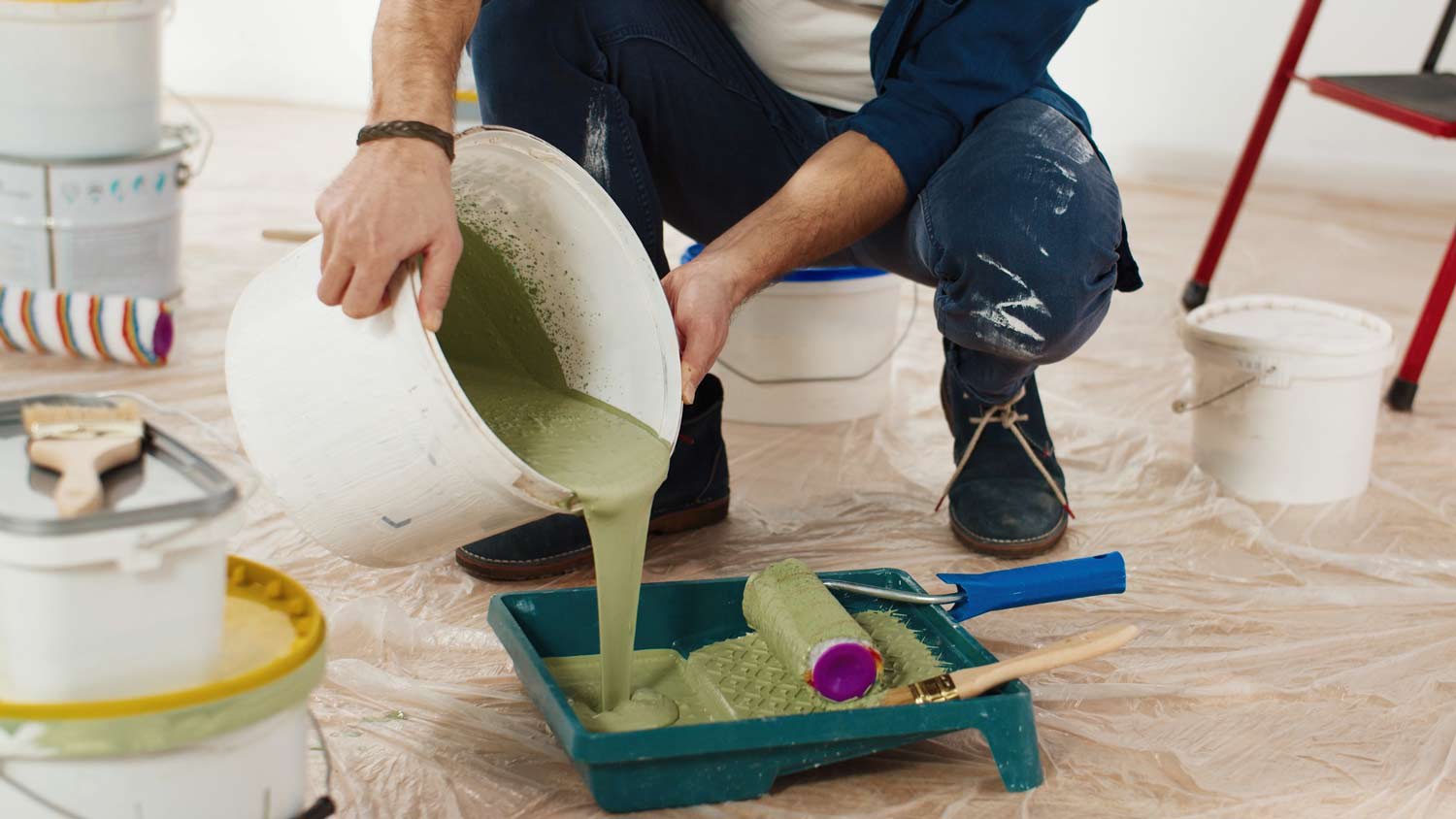 man pouring paint into tray