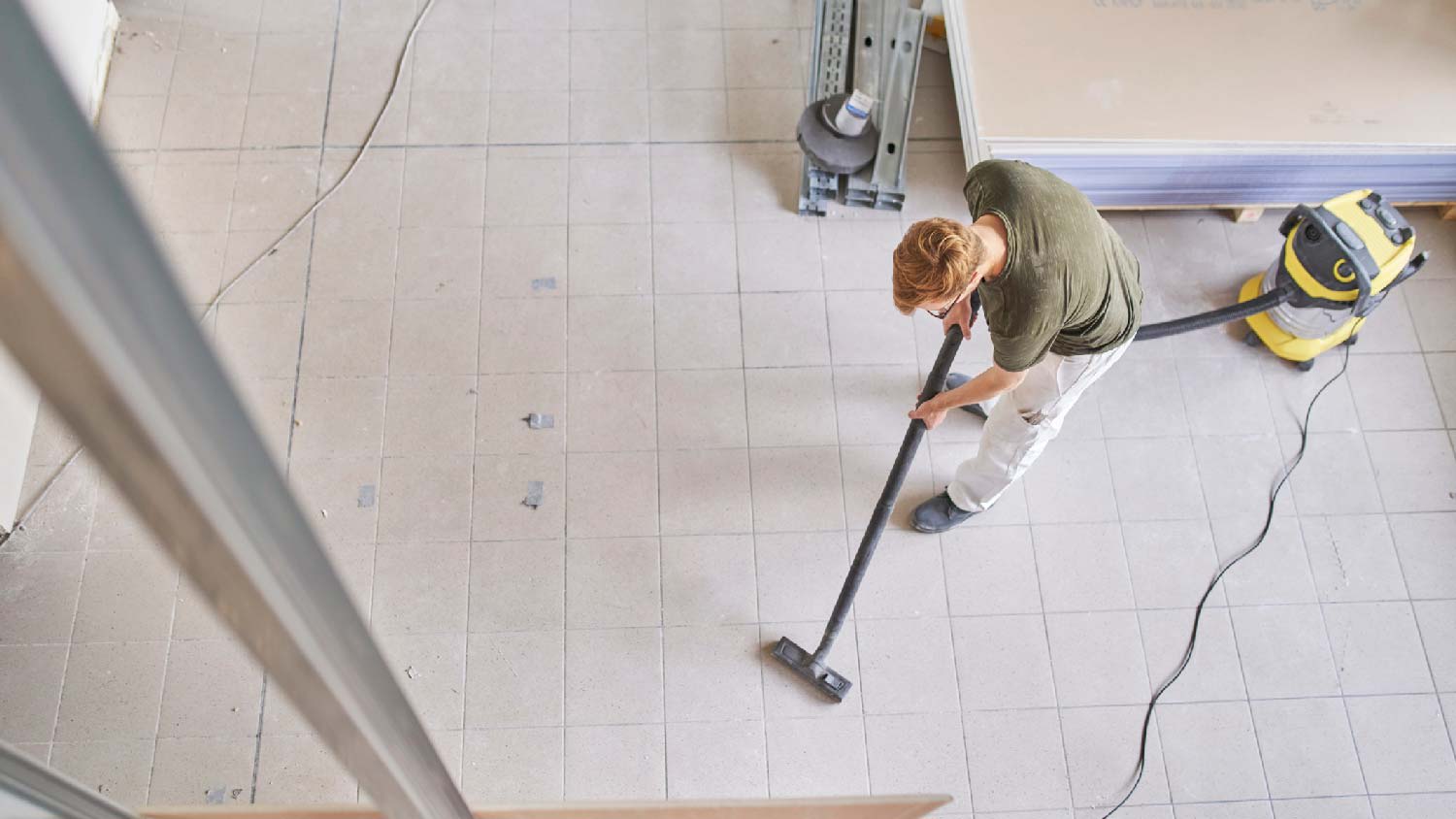 A man vacuuming drywall dust particles off the floor