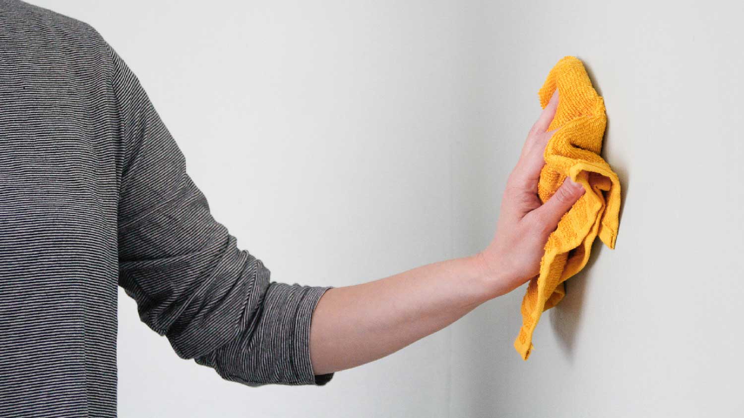 A woman dusting a drywall with a cloth