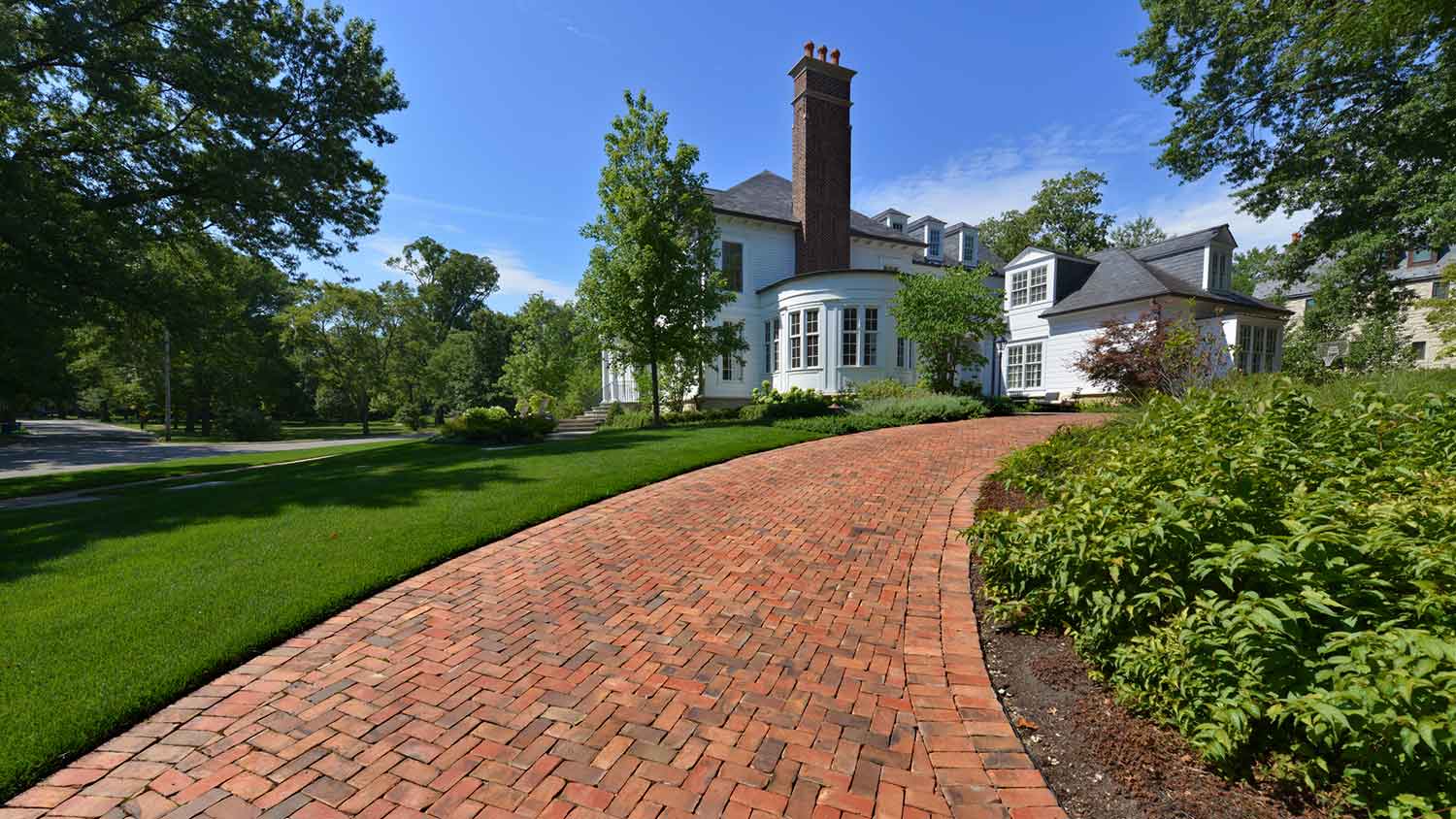 white house with brick paver driveway