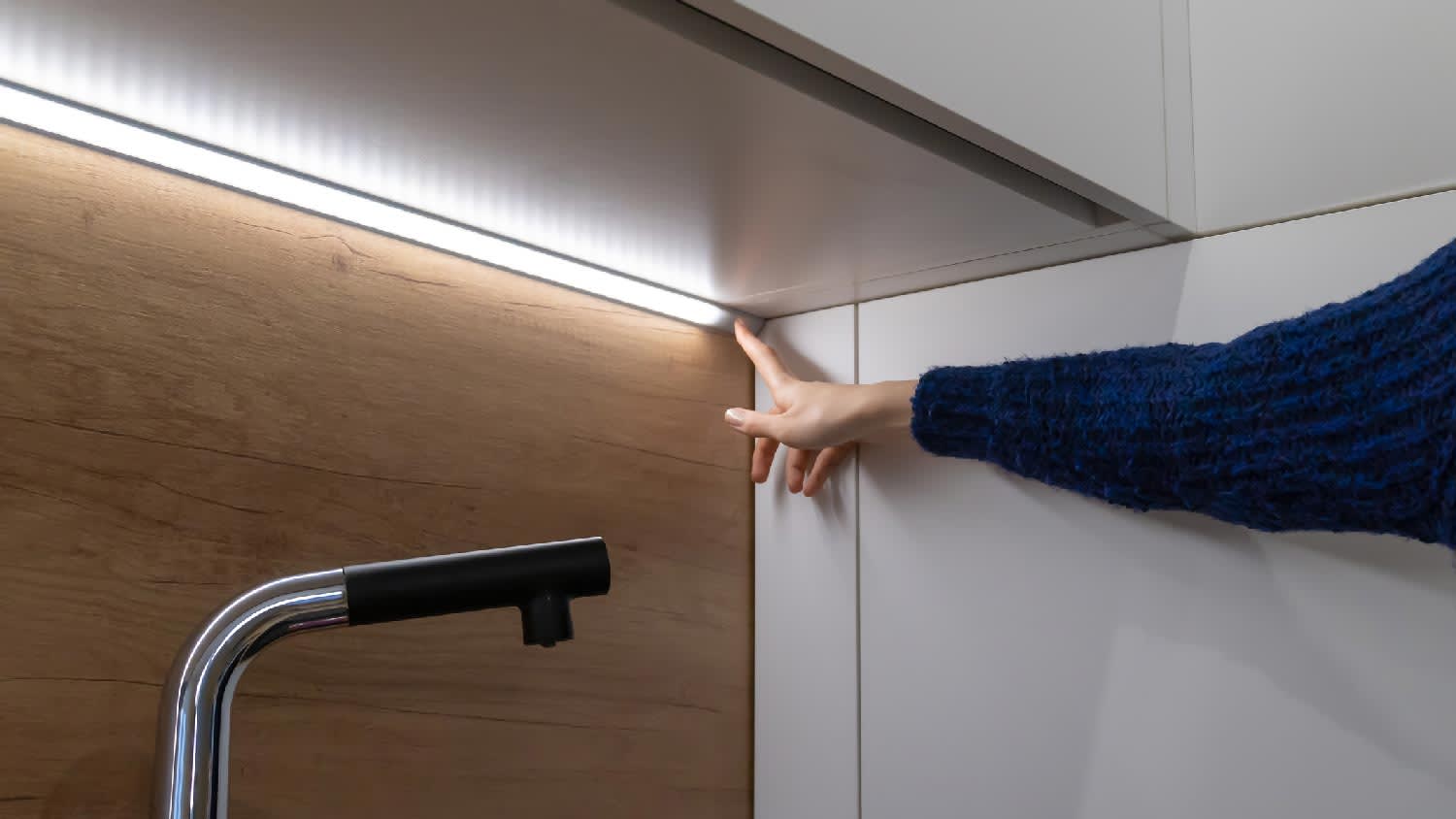 A woman turning on an under-cabinet light