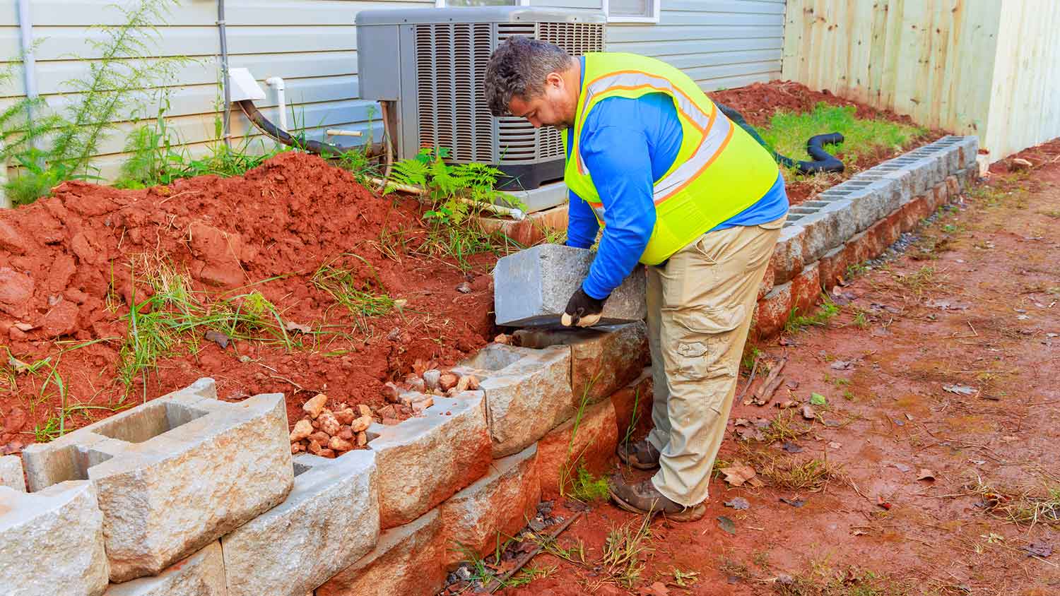 Professional installing a new retaining wall next to the house