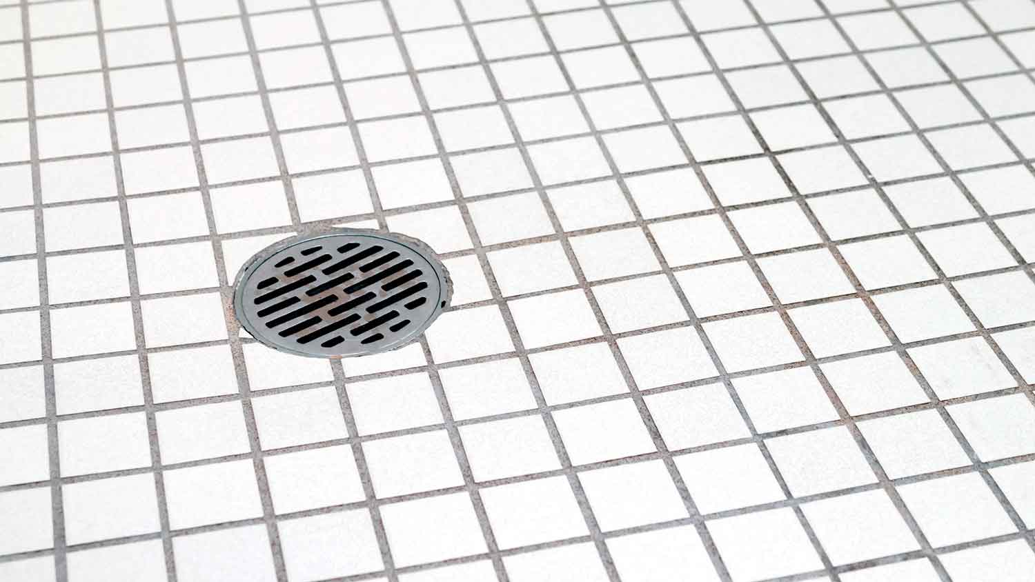 Silver grid installed on top of a center shower drain