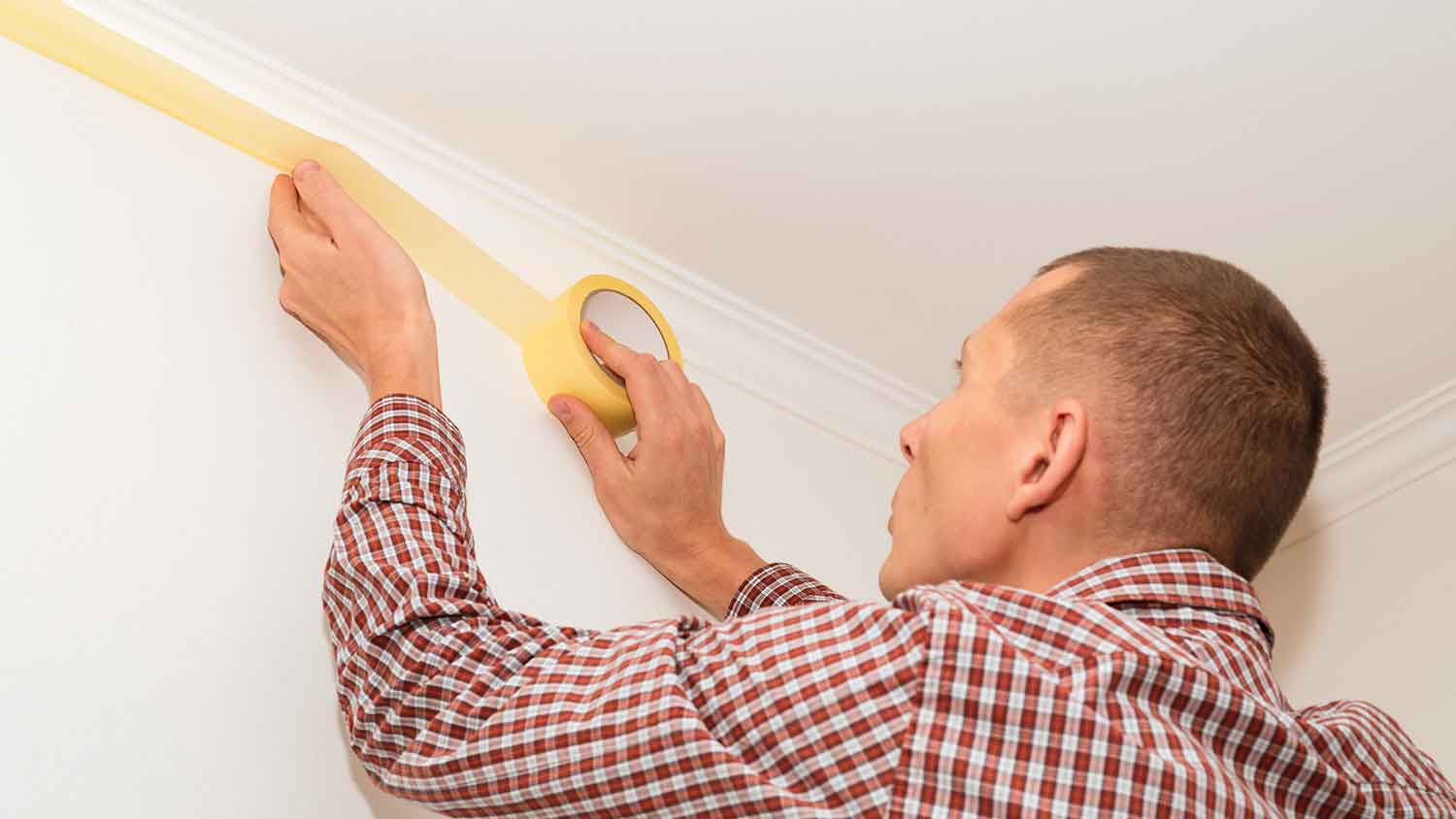 Handyperson taping off the wall with painter’s tape