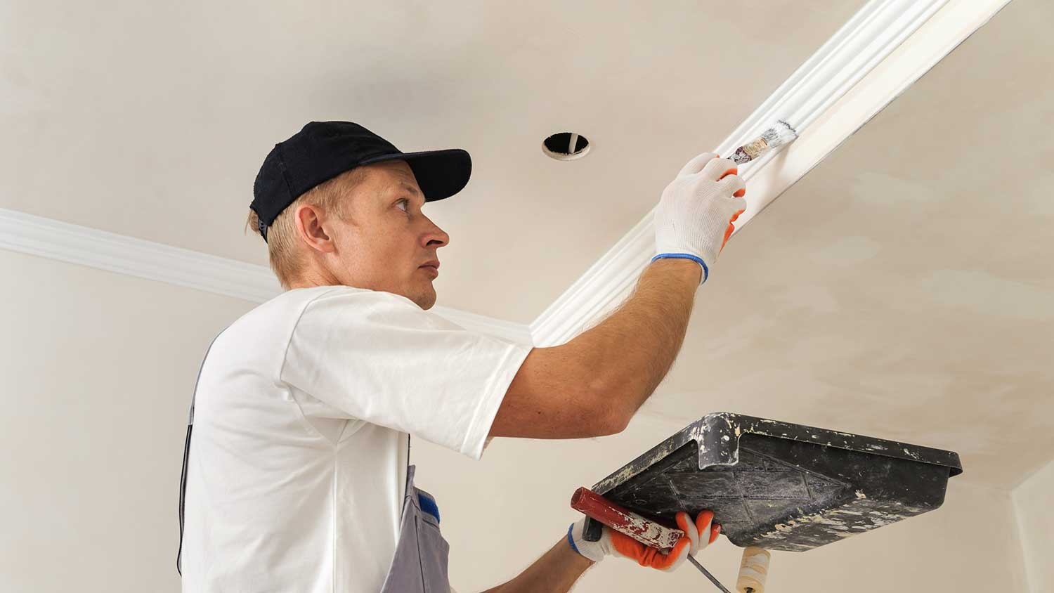 Handyperson using a brush to paint crown molding