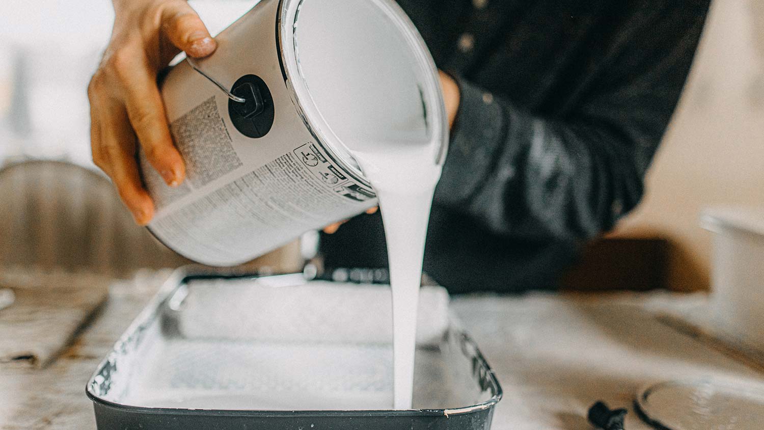 A person pouring paint in the paint tray