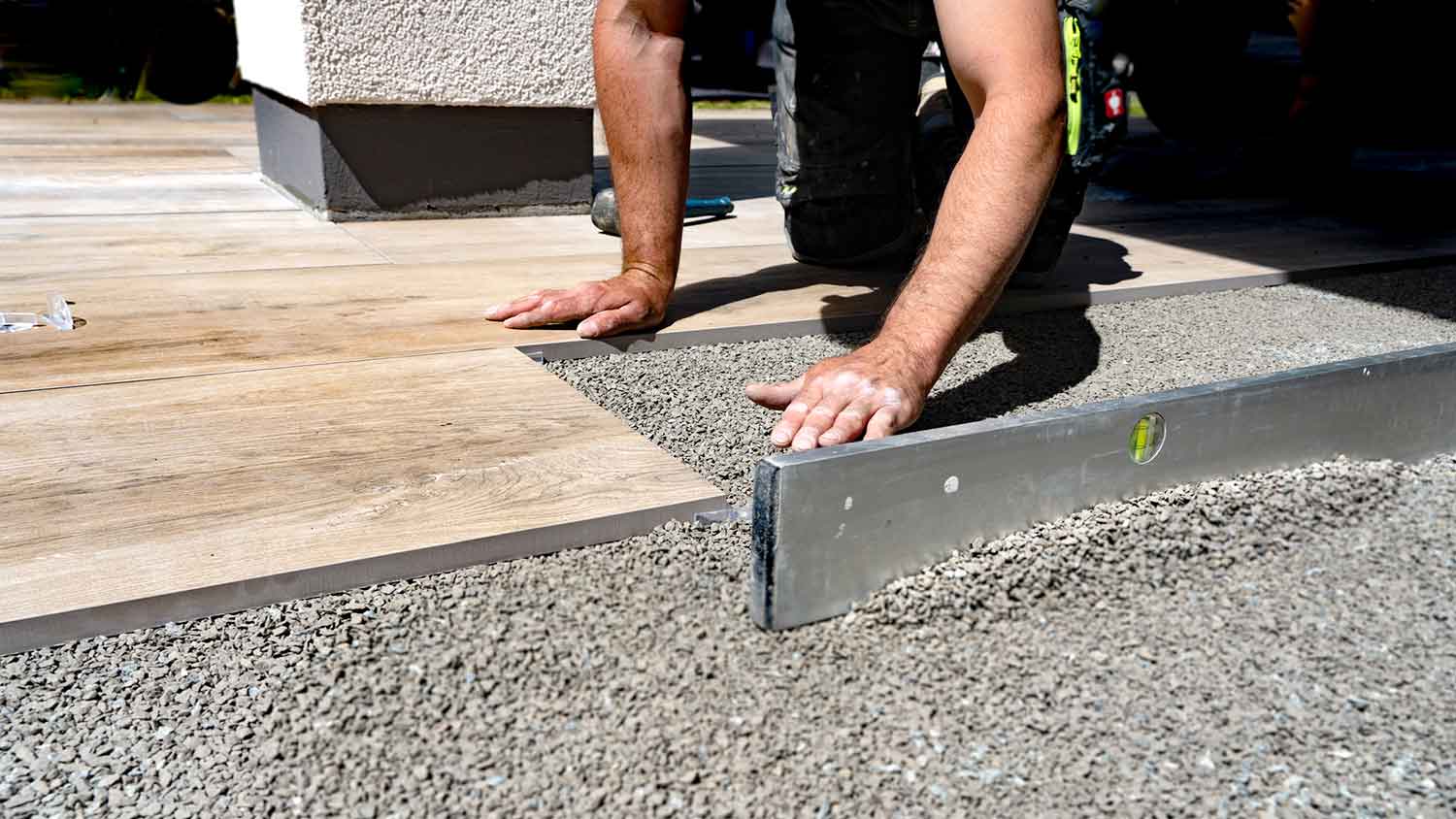 Contractor laying new patio slabs on top of a layer of gravel