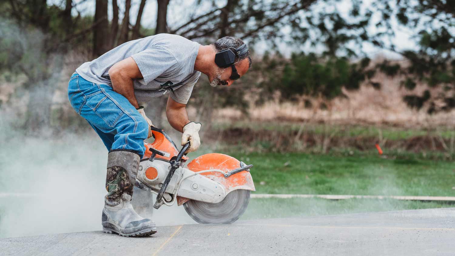 man with safety gear cutting concrete
