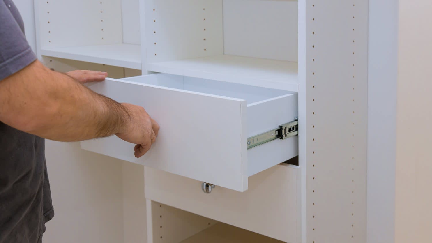 man installing drawer in closet cabinet