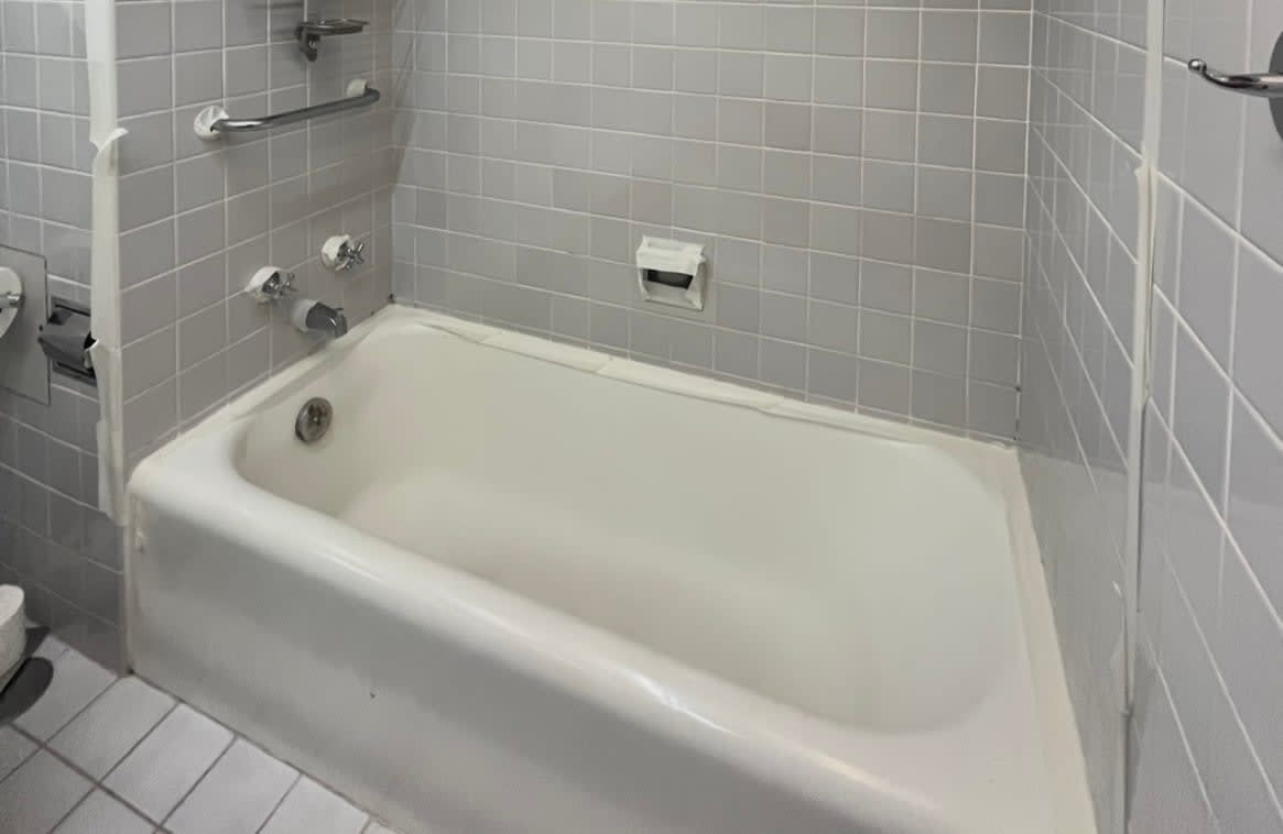 Outdated bathtub with gray tiles and white cast iron tub