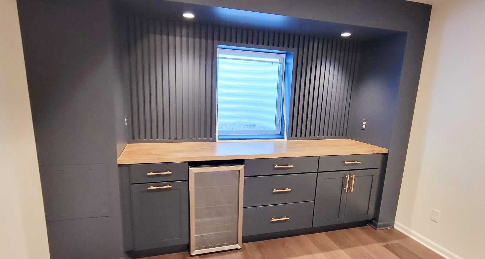 A wetbar frames an egress window. The wetbar features drawer and cabinet storage with a butcher block topper.