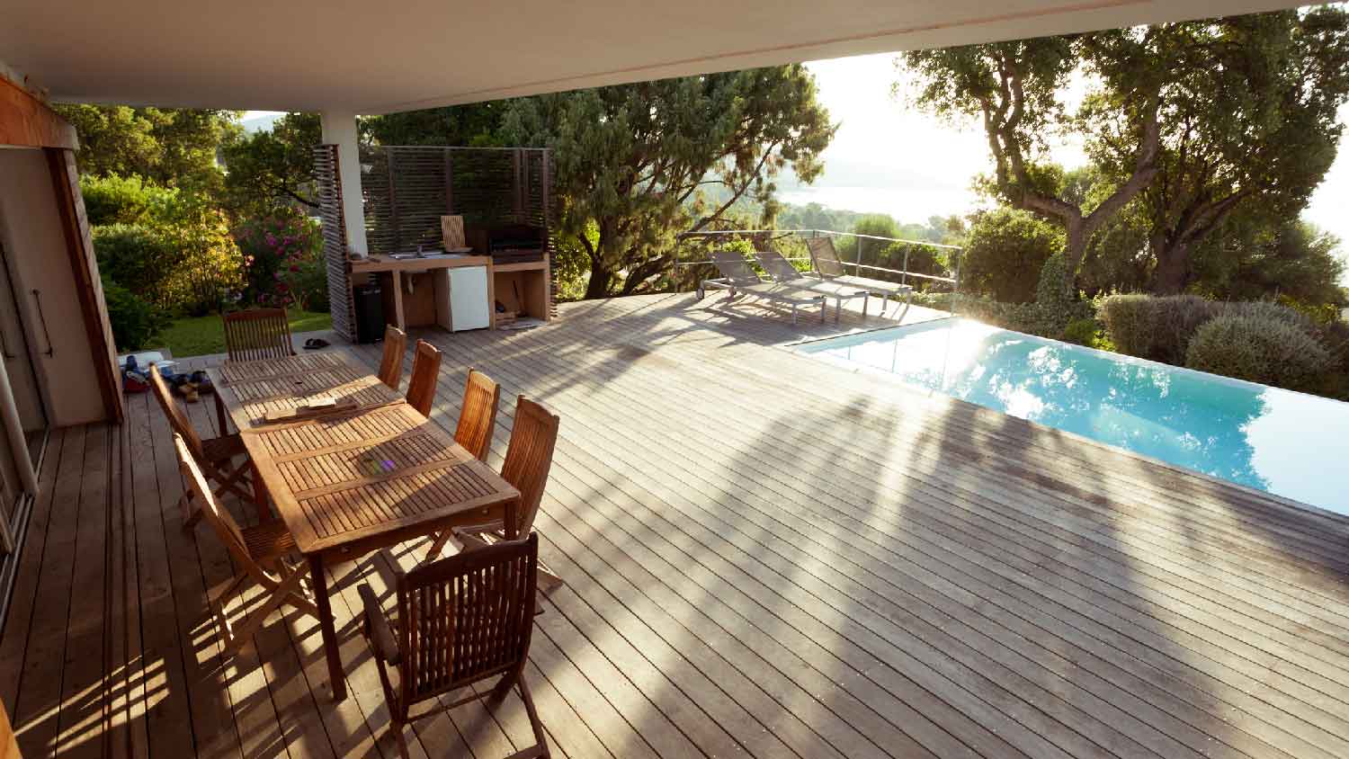 A luxury house with a wooden deck next to a pool