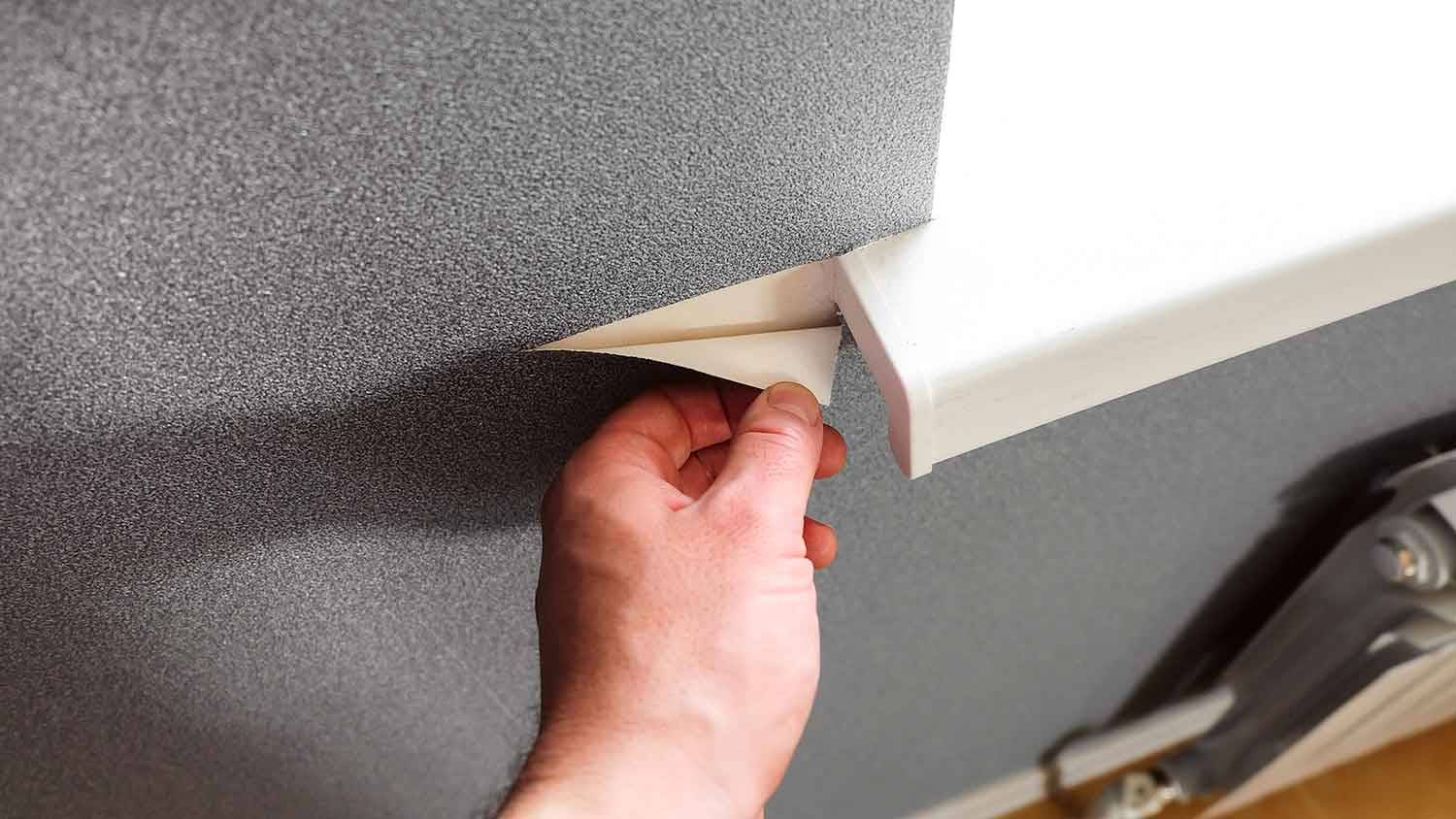 Person removing vinyl wallpaper from the wall