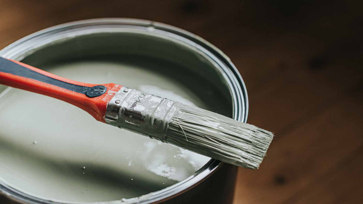 A paintbrush sitting atop a can of paint.