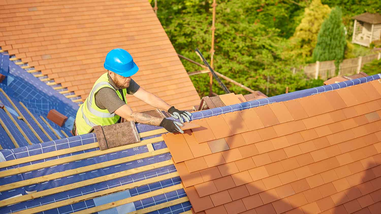 A worker installing clay tiles on a roof