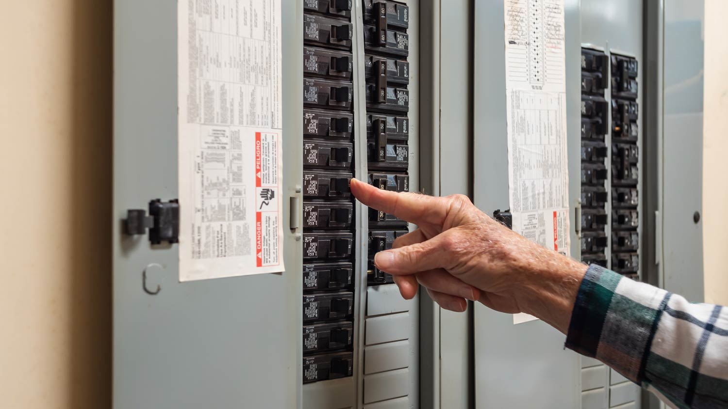 man turning on switch from circuit breaker