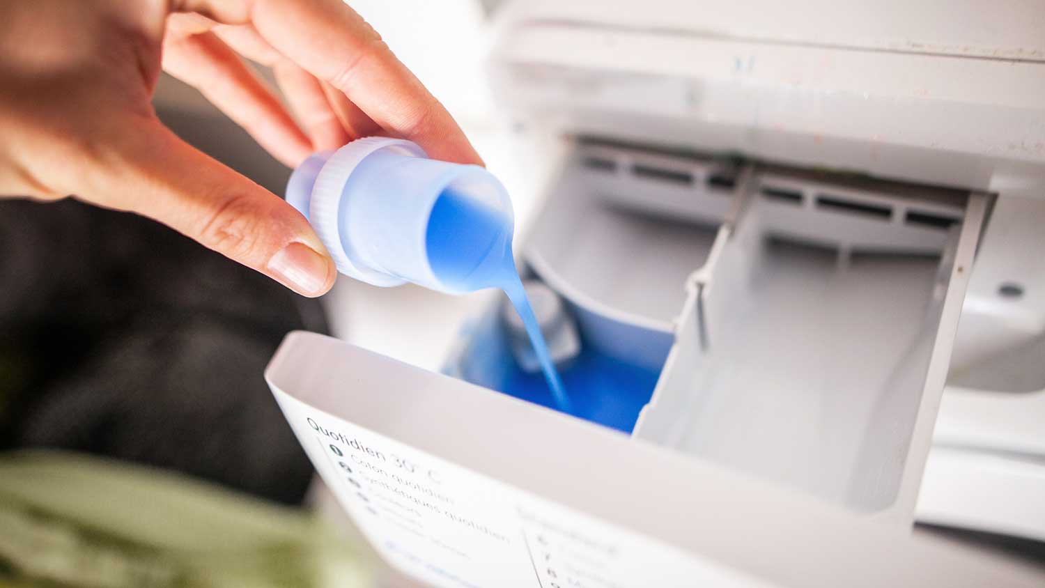 Pouring liquid laundry detergent in soap dispenser