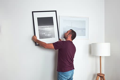 Man hanging pictures on the wall