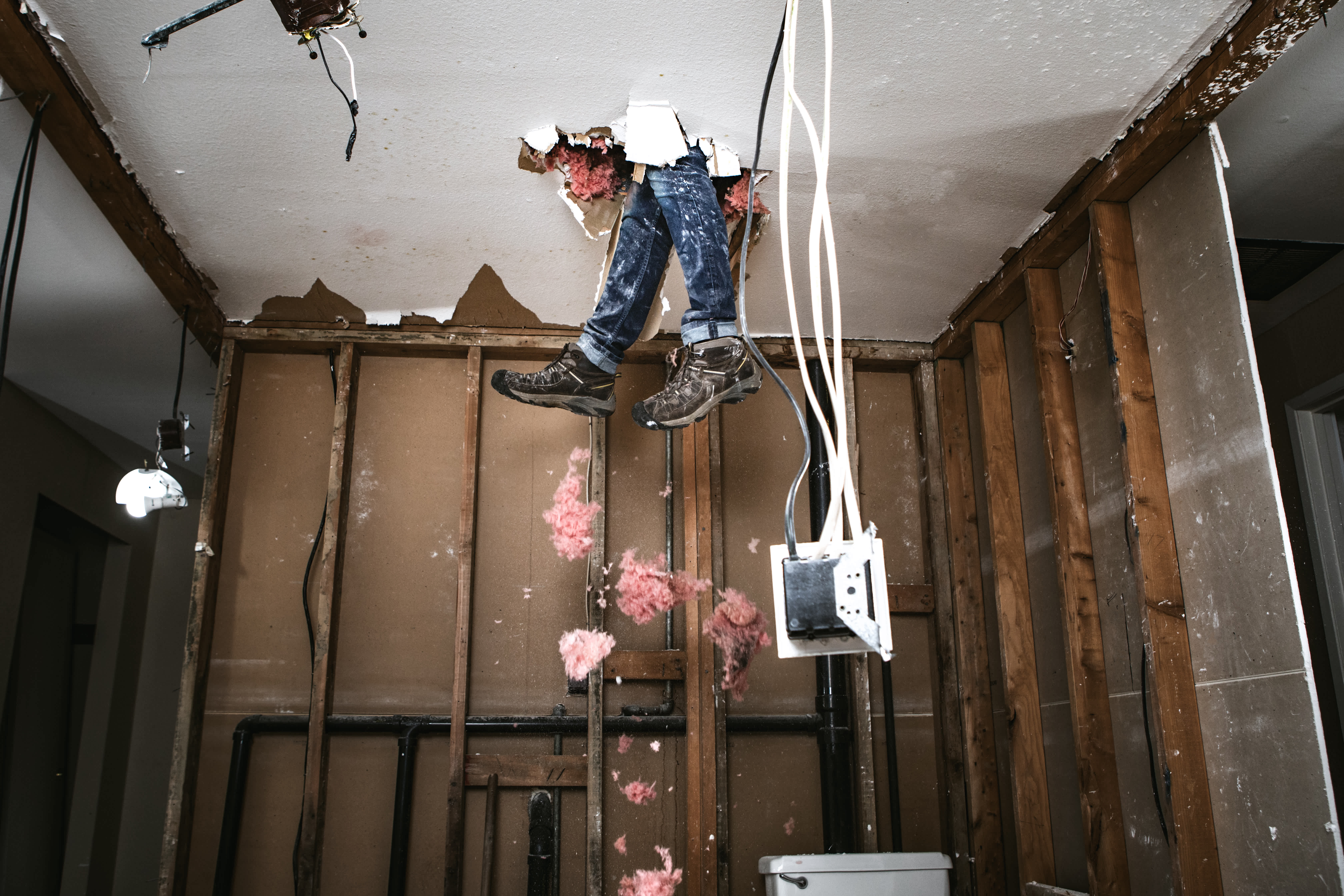 Feet and legs dangling from hole in ceiling of unfinished room