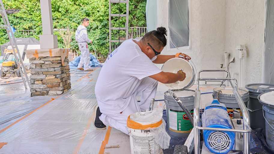 Painters Silvio and Anthony from Laguna Painting prepare paint and equipment, with surfaces protected for an exterior project.