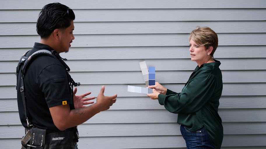 Angie Hicks shows paint swatches to the pro painting the siding