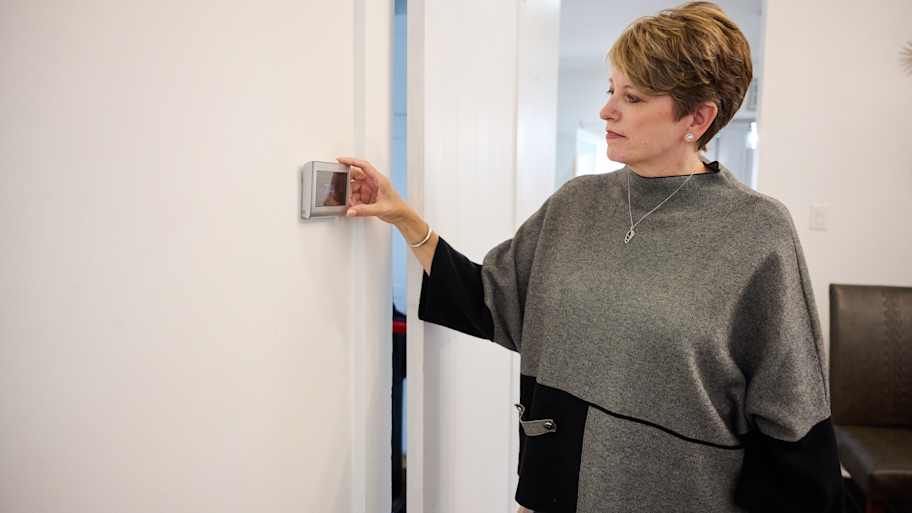 Angie Hicks looking at the smart thermostat installed in this home