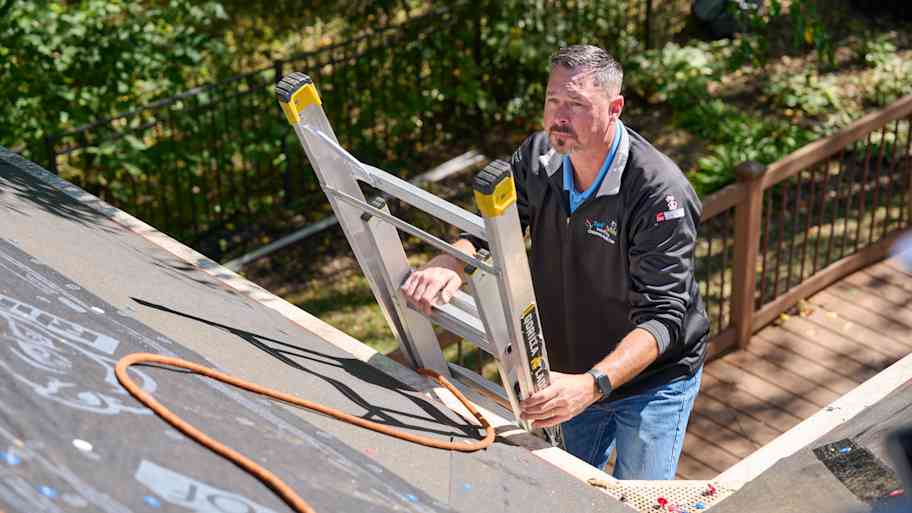Man climbing on roof with ladder.