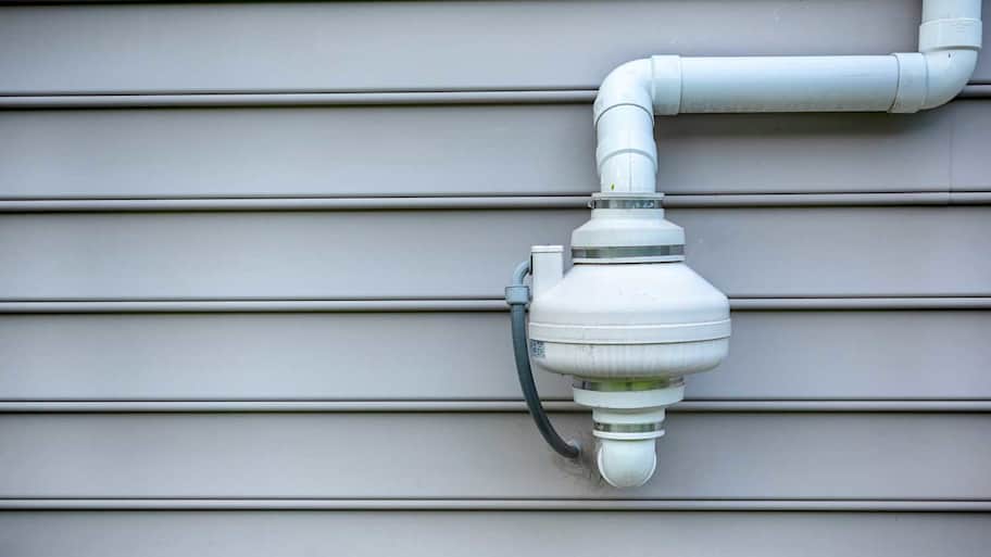 Radon mitigation fan attached to outdoor wall