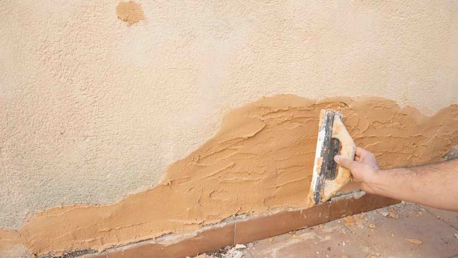 A person applying clay plaster with a trowel