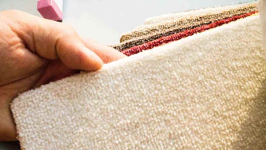 A hand feeling some carpet samples