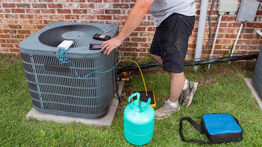 An HVAC technician adds refrigerant to an air conditioning unit