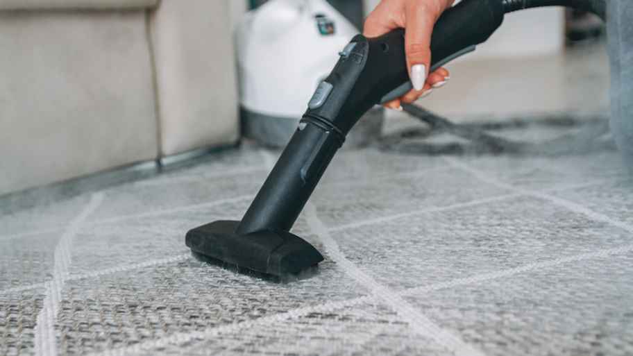 a steam cleaner cleaning a gray and white carpet with steam in the air