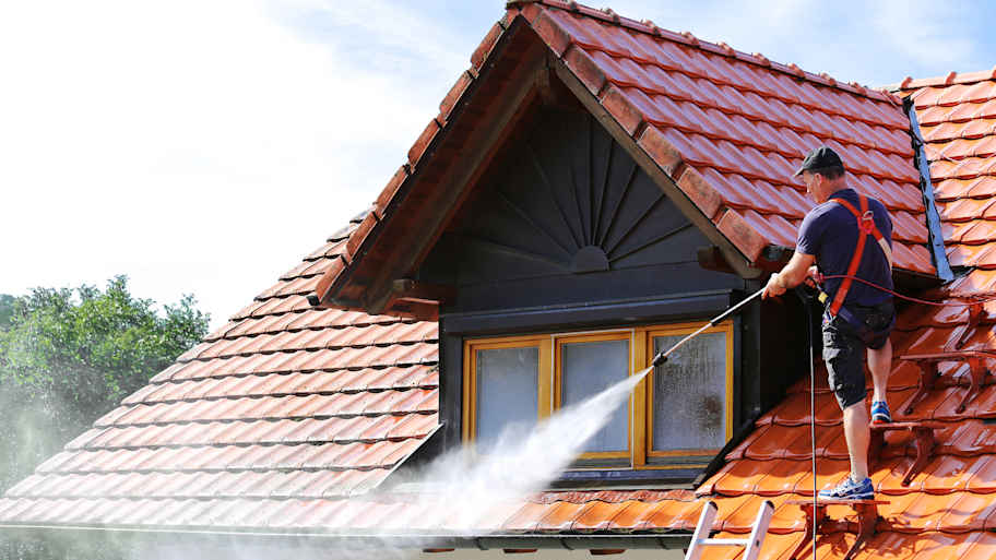 worker cleaning roof with high pressure hose