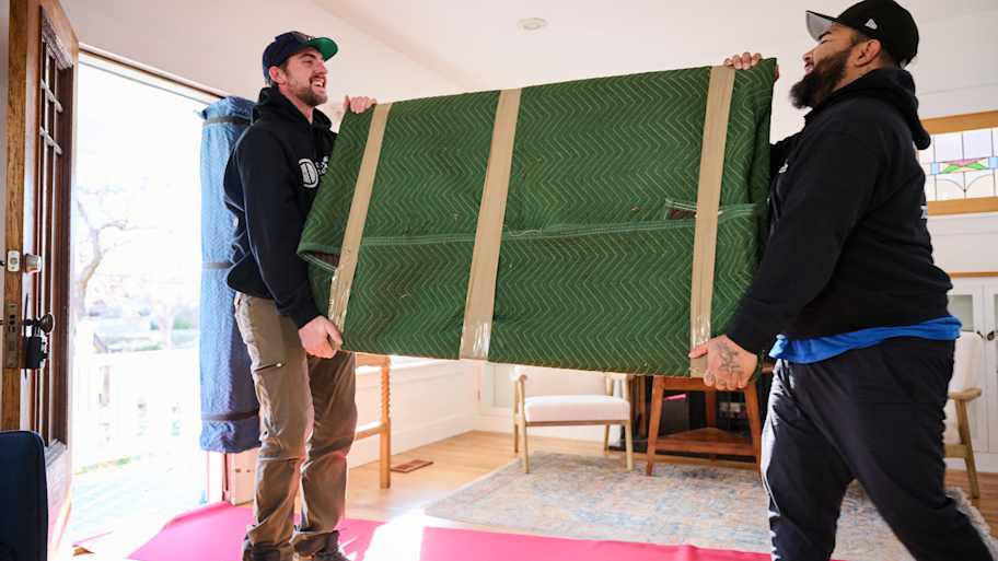 Men moving large wrapped up mirror.