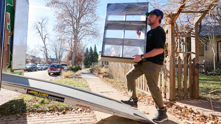 Man carrying furniture onto a moving truck.