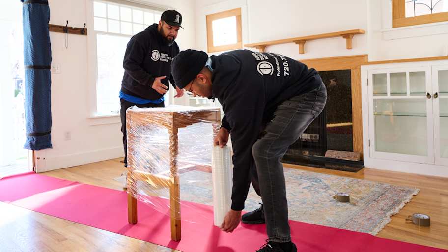 Two men wrapping up furniture.