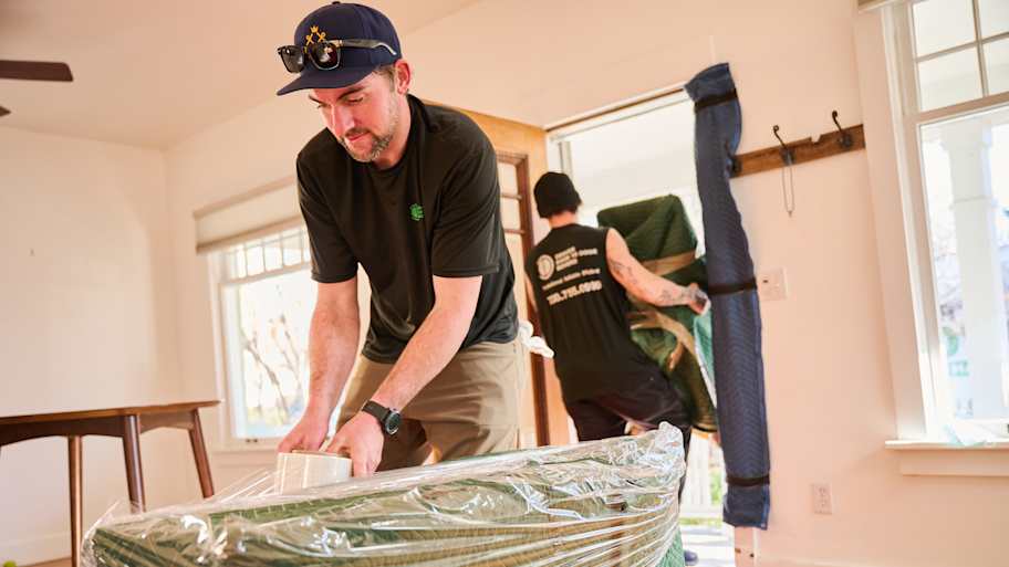 Moving men wrapping furniture for move.