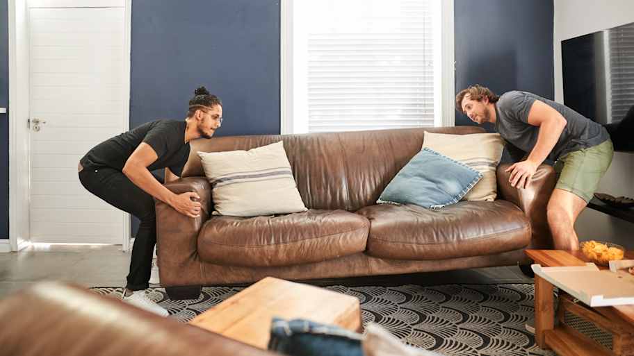 Two friends moving a living room sofa
