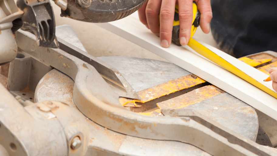 Carpenter measuring baseboard before cutting